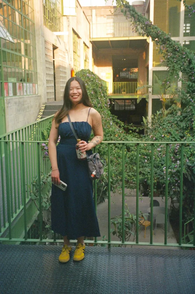 Selina smiling in a navy strapless outfit on a plant-filled balcony in Mexico City